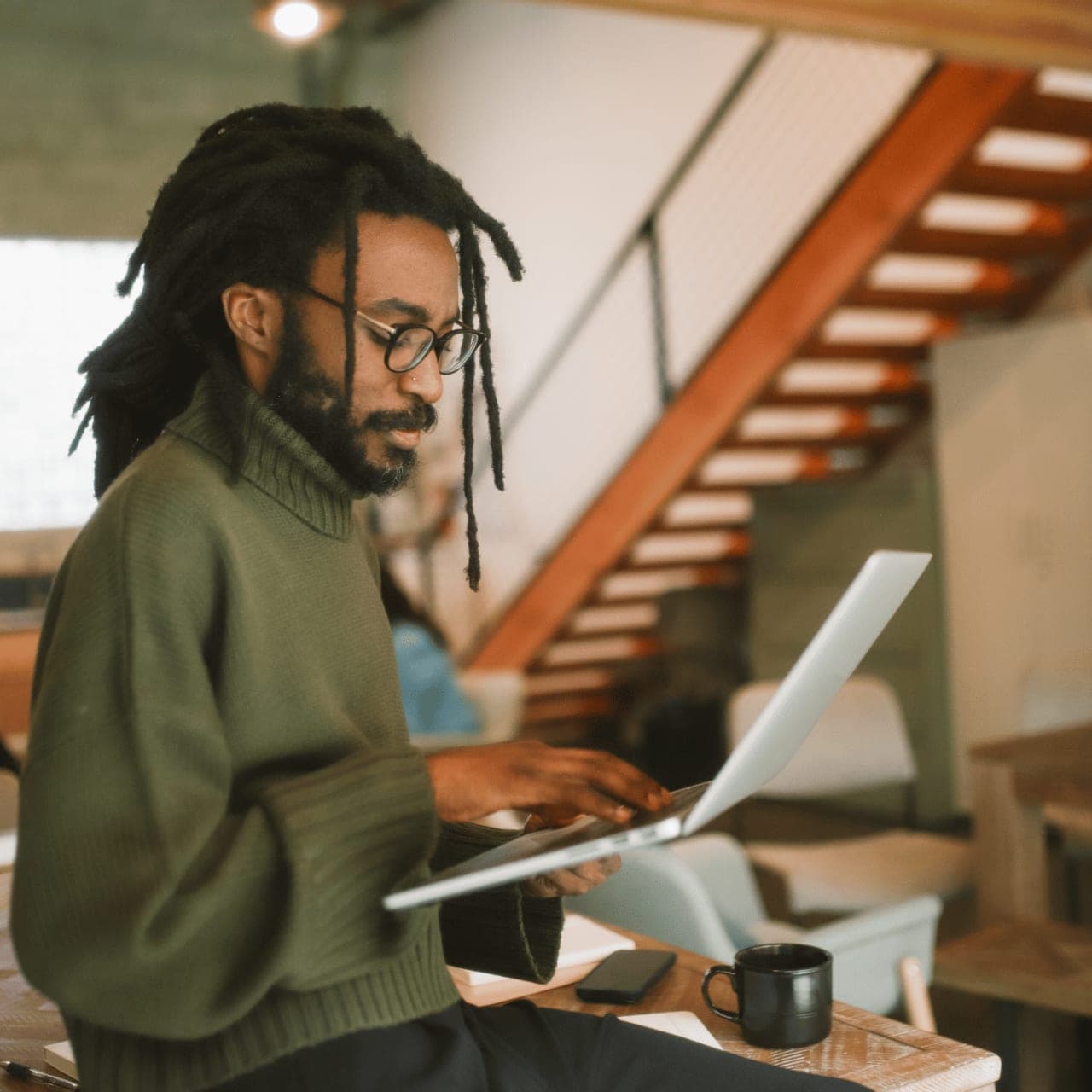 A person working at a desk with a laptop, reading and taking notes