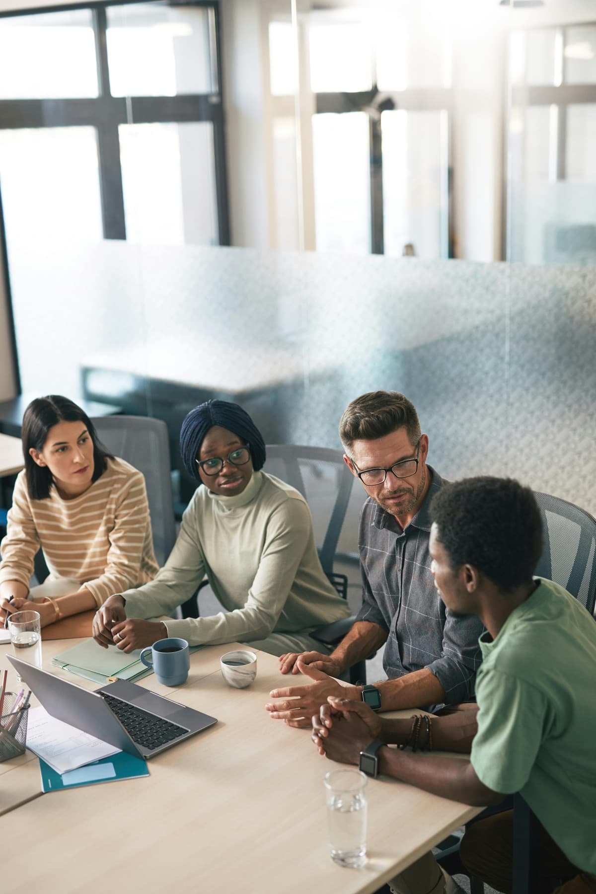 A diverse agency team sitting around a conference table reviewing a client security questionnaire on a laptop